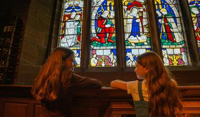 Two young girls looking at a stained glass window