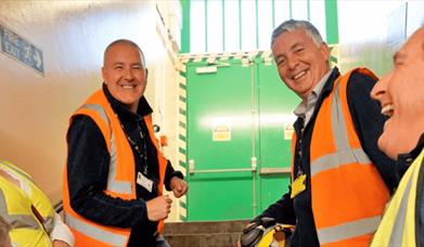 Three people wearing high-vis jackets and smiling.
