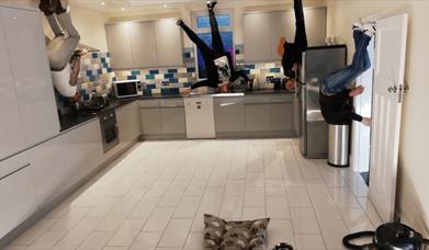 A photo illusion of people standing upside down in a kitchen.