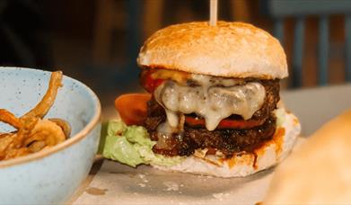 A burger with chips in a bowl.