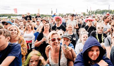 A crowd watches the stage at an outdoor festival.