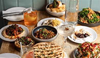 A table full of Mediterranean and Middle Eastern food with drinks.