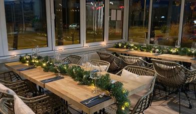 Tasting Bar & Kitchen interior tables at night with seats and foiliage